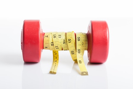 Red dumbbells weight with measuring tape for diet concept on white backgroundの写真素材