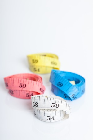 Close up of four colorful measuring tapes on white backgroundの写真素材