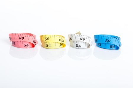 Close up of four colorful measuring tapes on white background