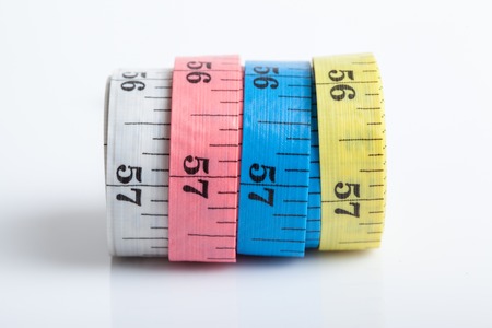 Close up of four colorful measuring tapes on white background