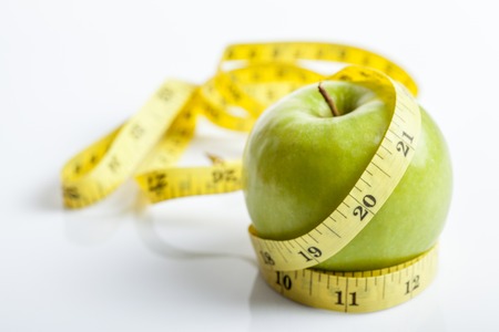 Measuring tape with green apple on white backgroundの写真素材