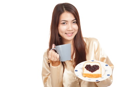 Asian woman in pajamas with coffee and heart shape jam on bread  isolated on white backgroundの写真素材