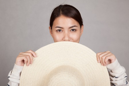 Beautiful Asian girl with sun hat in front of her  on gray backgroundの写真素材