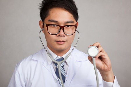 Asian male doctor with  stethoscope on gray backgroundの写真素材