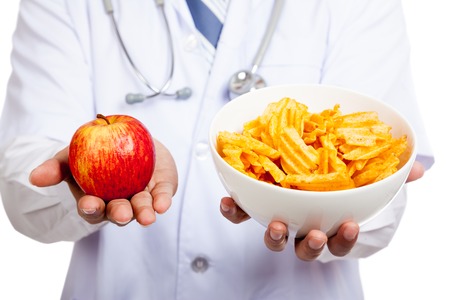 Close up of Asian male doctor with red apple and potato chipsの写真素材