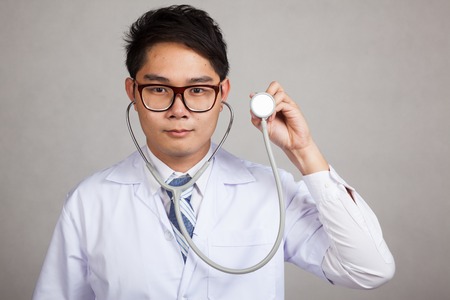 Asian male doctor with  stethoscope on gray backgroundの写真素材