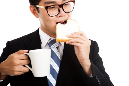 Asian businessman eat bread and coffee as breakfast  isolated on white backgroundの写真素材