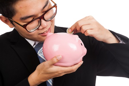 Close up of Asian businessman  smile put a coin to a pink piggy bankの写真素材