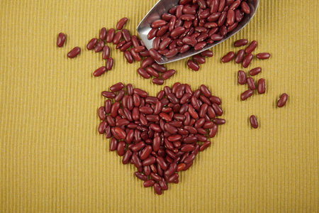 Heart shape of red kidney beans with scoop on green clothの写真素材