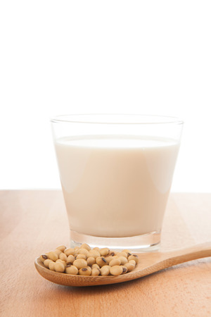 Soy milk in glass with soybeans and wooden spoon on wood tableの写真素材