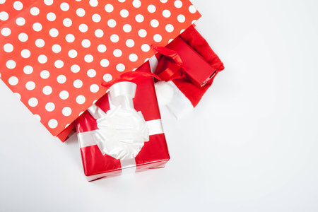 Red gift boxes and and christmas hat in shopping bags on white backgroundの写真素材