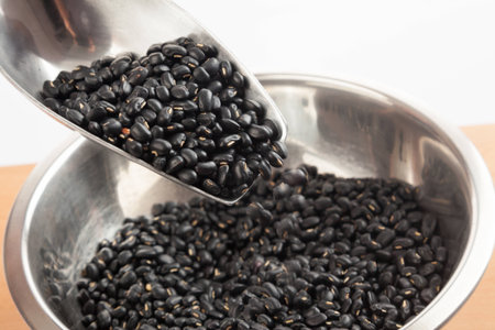 Black beans in bowl with transfer scoop on wood table