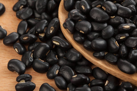 Black beans with wooden spoon on wood background