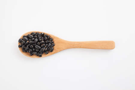 Black beans with wooden spoon on white background