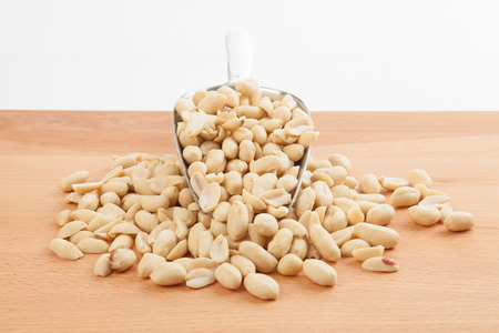 Peeled peanuts with transfer scoop on wood table