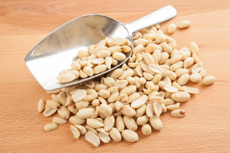 Peeled peanuts with transfer scoop on wood table