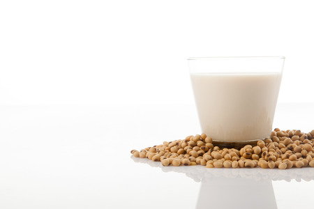 Soy milk in glass with soybeans on white backgroundの写真素材