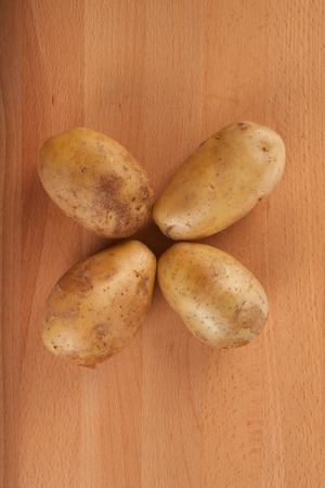 Top view of four  potatoes on wooden tableの写真素材