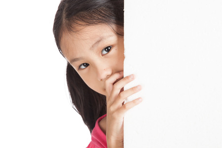 Little asian girl peeking behind a white board  isolated on white backgroundの写真素材