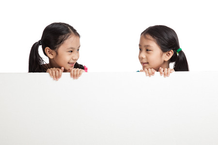 Happy Asian twins girls  behind white blank banner on white backgroundの写真素材