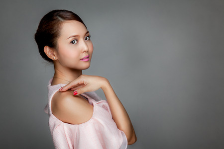 Happy beautiful Asian girl  in pink dress on gray backgroundの写真素材