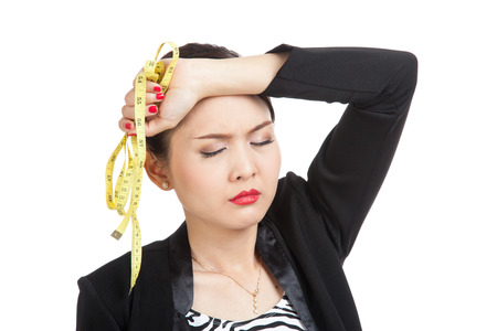 Unhappy young Asian business woman with measuring tape  isolated on white backgroundの写真素材