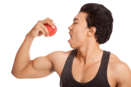 Muscular Asian man flexing biceps with red apple  isolated on white backgroundの写真素材
