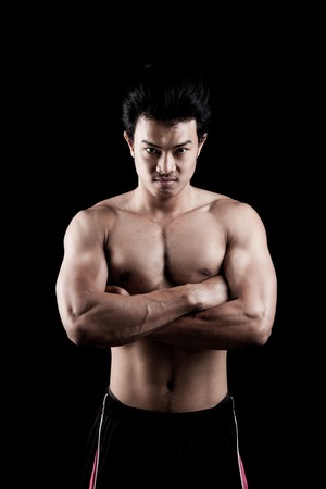 Muscular Asian man show his body on dark backgroundの写真素材