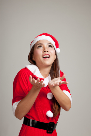 Asian Christmas girl with Santa Claus clothes on gray backgroundの写真素材