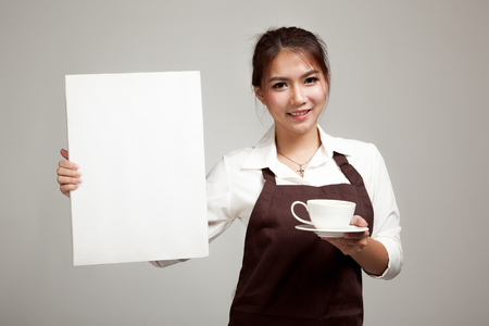 Waitress or barista  in apron  holding coffee and blank sign on gray backgroundの写真素材