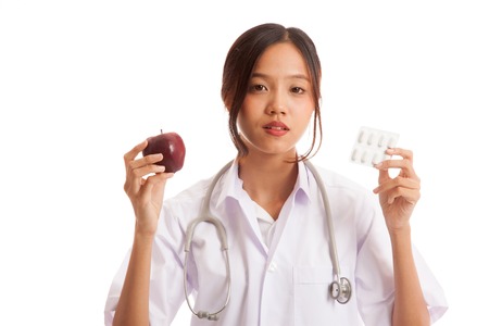Young Asian female doctor with pills and apple  isolated on white background .の写真素材