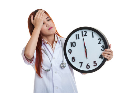 Young Asian female doctor headache with a clock  isolated on white background.の写真素材