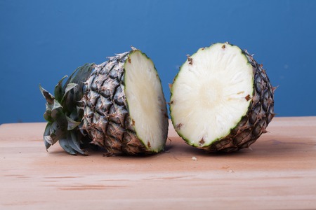 Half cut of pineapple on wooden table and blue backgroundの写真素材