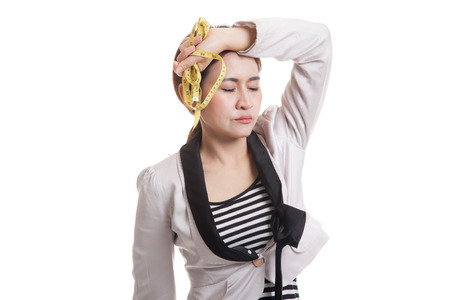Unhappy young Asian business woman with measuring tape  isolated on white background.の写真素材