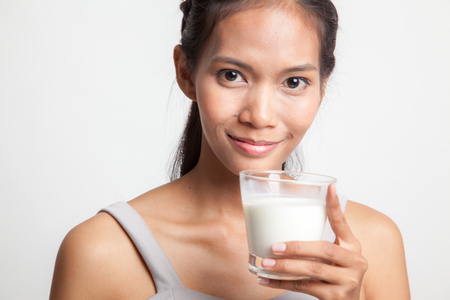 Healthy Asian woman drinking a glass of milk on white backgroundの写真素材