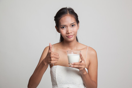 Healthy Asian woman drinking a glass of milk thumbs up  on gray backgroundの写真素材