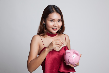 Asian woman with coin and pig coin bank on gray backgroundの写真素材