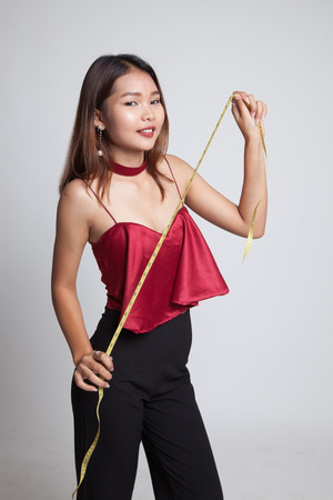 Young Asian woman with measuring tape on gray backgroundの写真素材
