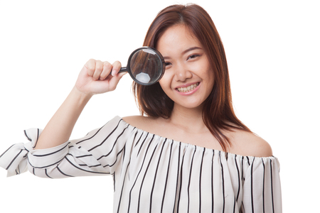 Young Asian woman with a magnifying glass isolated on white backgroundの写真素材