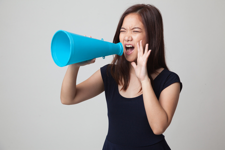 Beautiful young Asian woman announce with megaphone on gray backgroundの写真素材