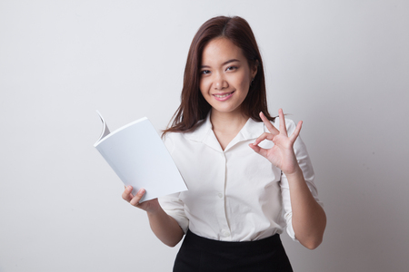 Young Asian woman show OK with a book on white backgroundの写真素材