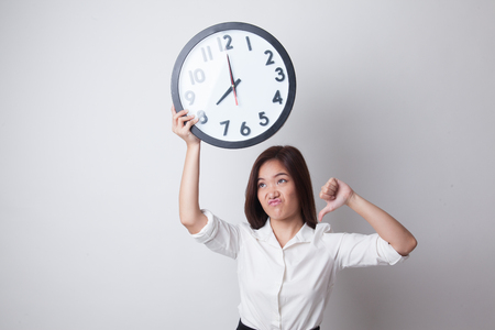 Young Asian business woman thumbs down with a clock on white backgroundの写真素材