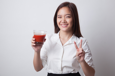 Young Asian business woman show victory sign with tomato juice on white backgroundの写真素材