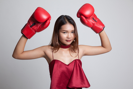 Young Asian woman with red boxing gloves on gray backgroundの写真素材