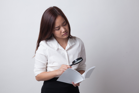 Asian woman with a book and magnifying glass on white backgroundの写真素材