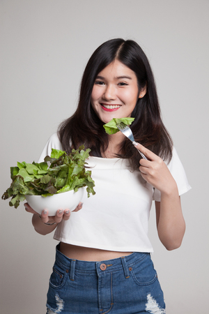 Healthy Asian woman with salad on gray backgroundの写真素材