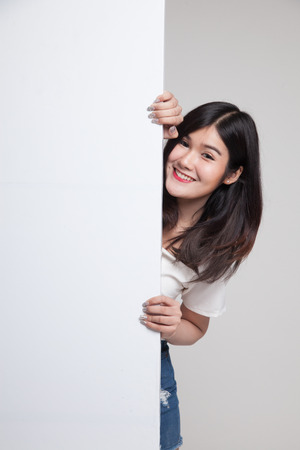 Young Asian woman with blank sign on gray backgroundの写真素材