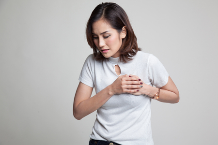 Young Asian woman got chest pain on gray backgroundの写真素材