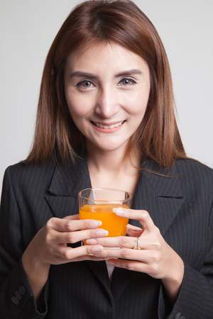 Young Asian woman drink orange juice on gray backgroundの写真素材