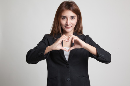Young Asian woman show heart hand sign on gray backgroundの写真素材